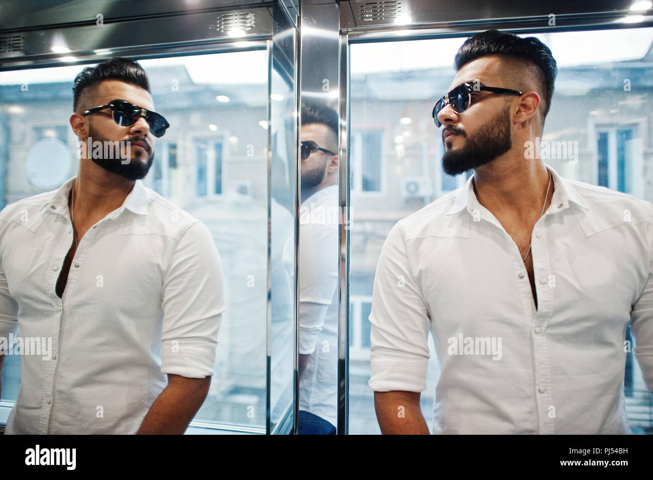 Stilvolle hohen arabischen Mann im weißen Hemd und Sonnenbrille bei Elevator innen gestellt. Stockfoto