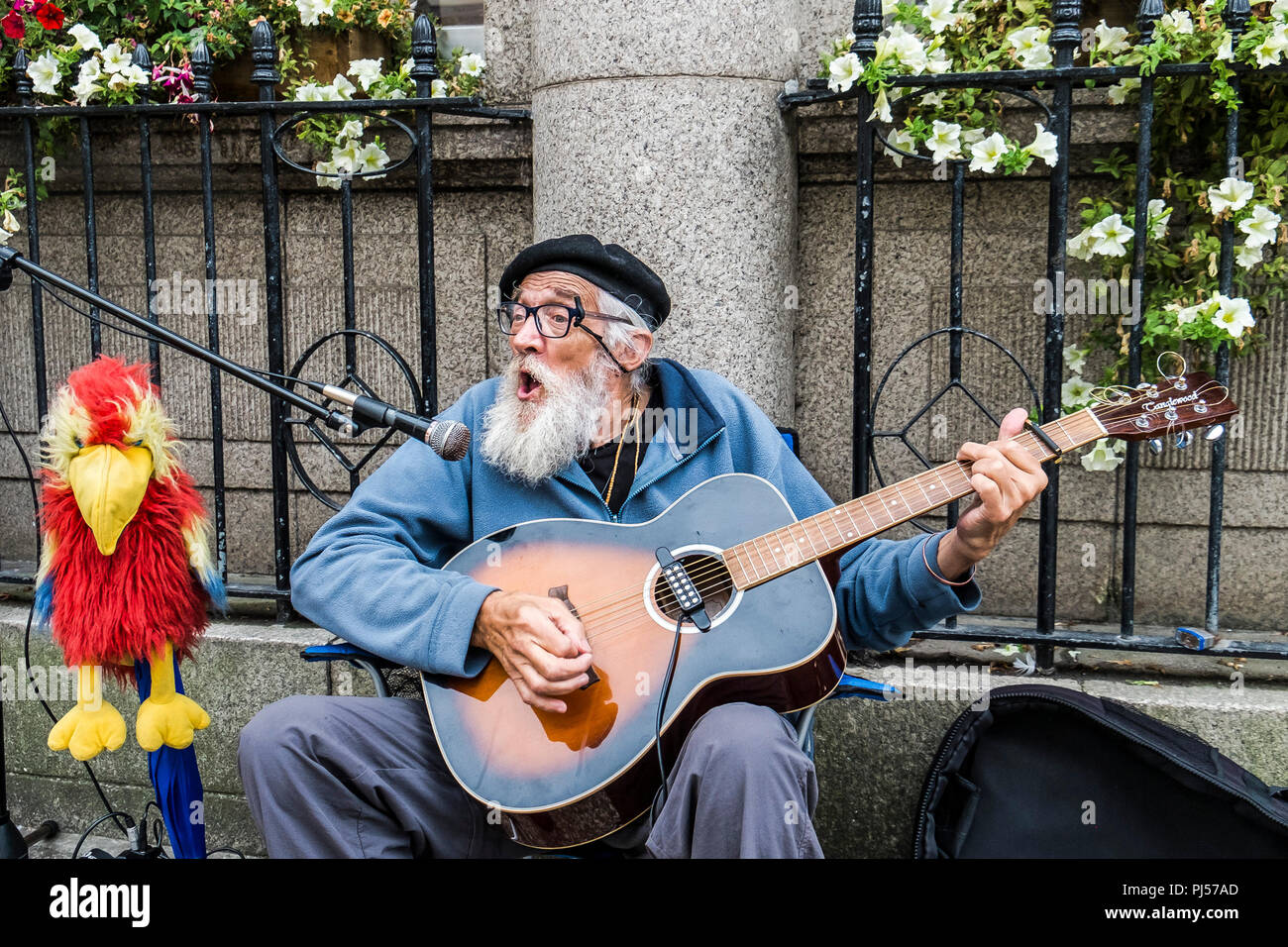 Eine ausgereifte busker Gitarre spielen und singen in einer Straße in Truro Cornwall. Stockfoto