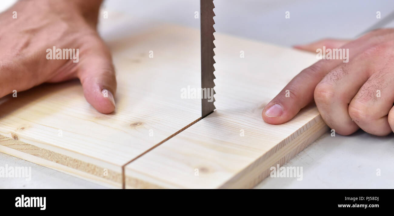 Schreiner in der Werkstatt sägt eine Holzplatte mit einer Säge - Detail Stockfoto