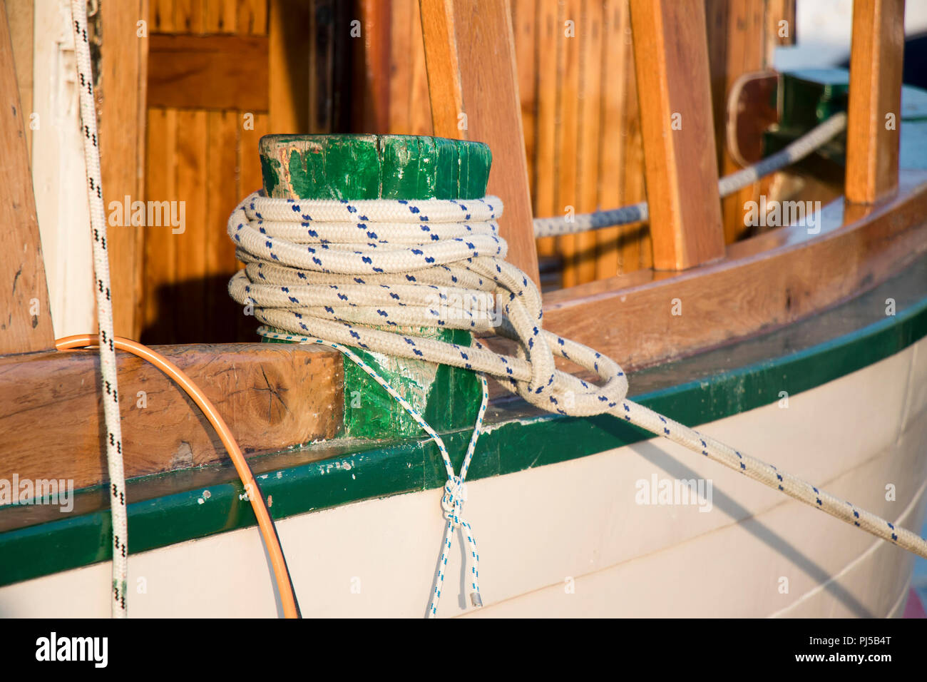 Detail eines hölzernen Segelboot, und ein Seil um einen bitt für die Befestigung am Ufer Stockfoto
