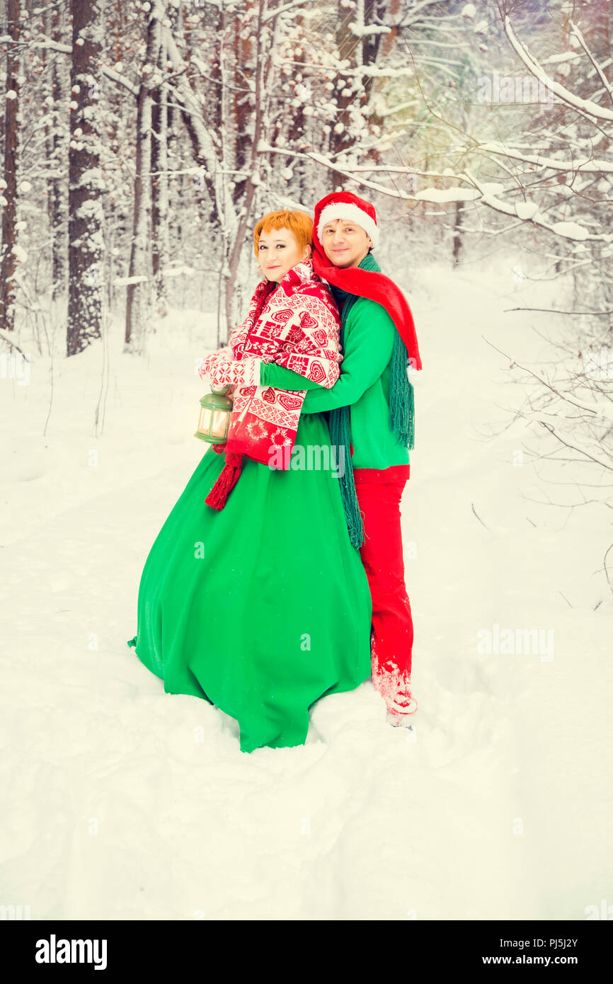 Junges Paar, Mann und Frau sind zu Fuß in Kostümen von Blumen, die typisch für die Elfen von Santa's Helfer in einem Winter Forest unter dem Schnee mit einem che Stockfoto