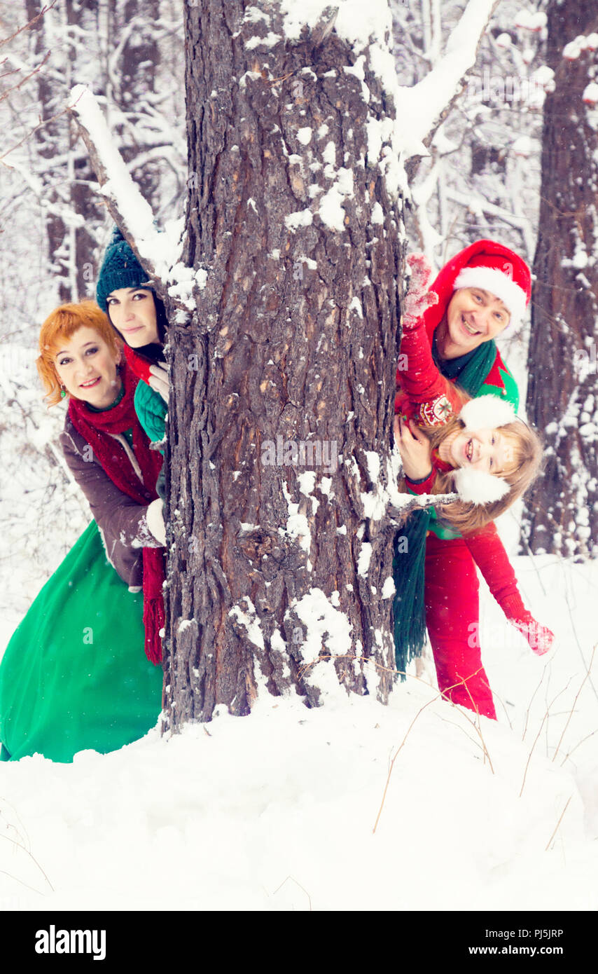 Familie in der traditionellen Weihnachtsstern Kostüme, Rot-Grün, Santa's Helfer - die Elfen, im Winter Wald mit einer Truhe von Geschenken und einem riesigen Candy Stockfoto