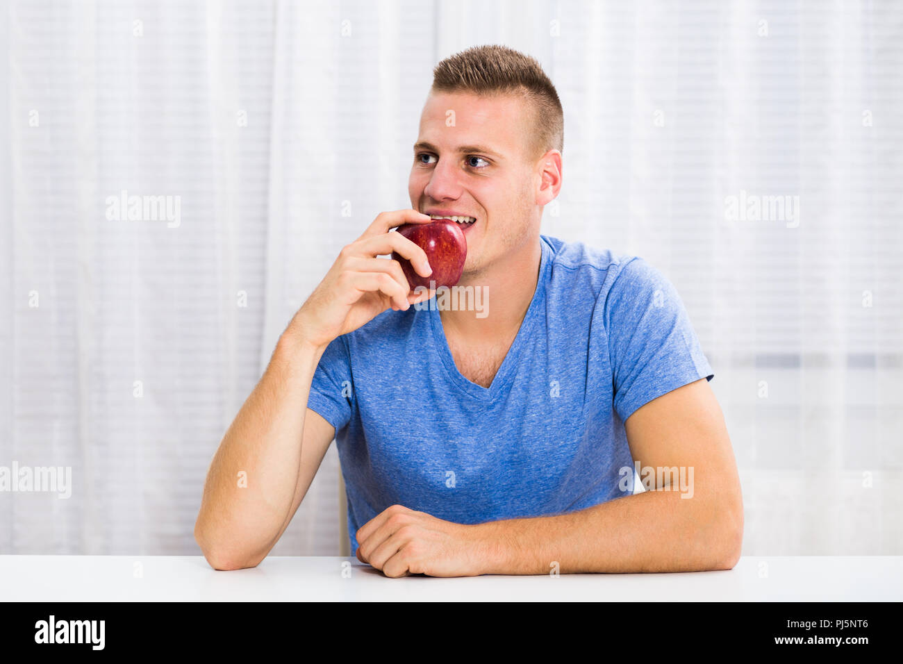 Junger Mann Apple zu Hause essen. Stockfoto
