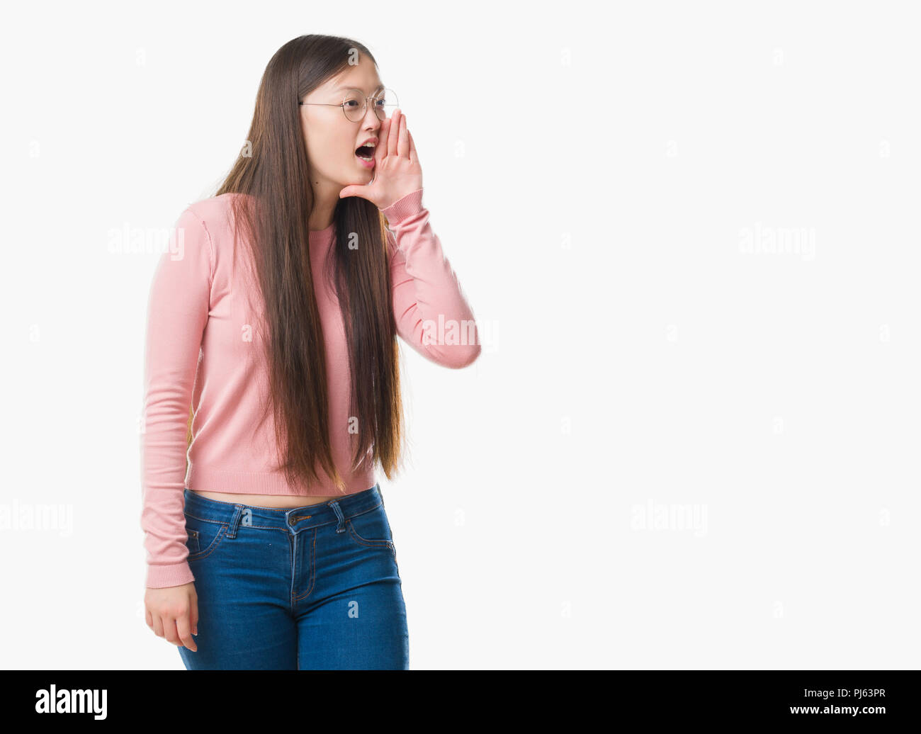 Junge chinesische Frau über isolierte Hintergrund Brille schreien und schreien laut mit Hand auf Mund-zu-Seite. Kommunikationskonzept. Stockfoto