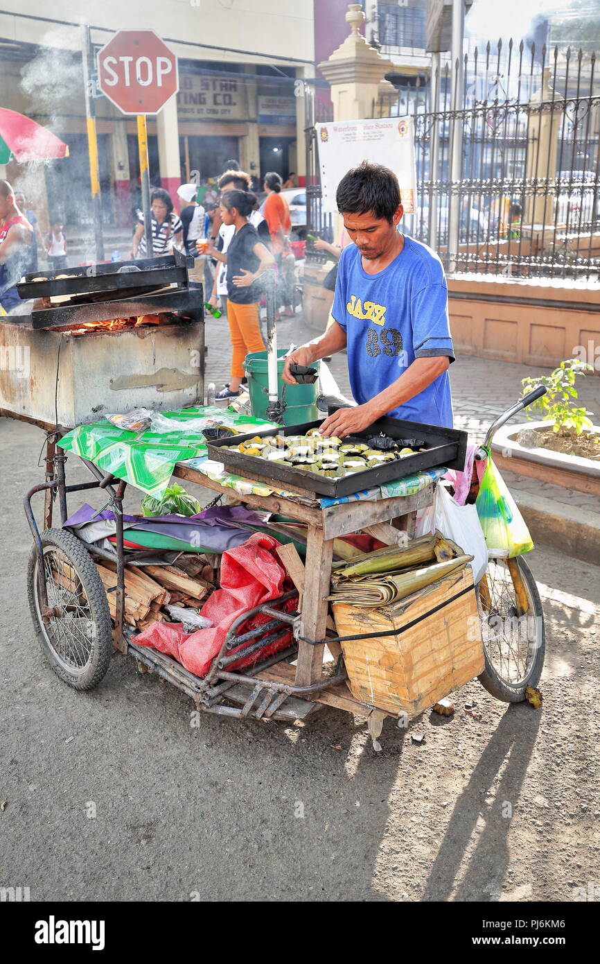 Cebu, Philippines-October 18, 2016: streetfood Verkäufer Köche und verkauft Philippinischen Köstlichkeiten aus ihrer Nahrung Fahrrad - Warenkorb angeheizt durch Brennholz in stationiert Stockfoto