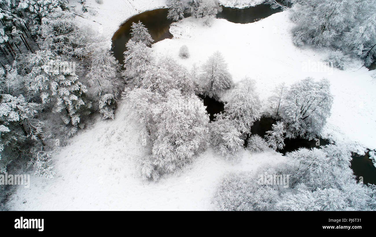 Winter Landschaft Luftbild Drohne anzeigen. Fluss zwischen Bäumen von Schnee bedeckt. Winter Natur. Snowy Wetter. Stockfoto