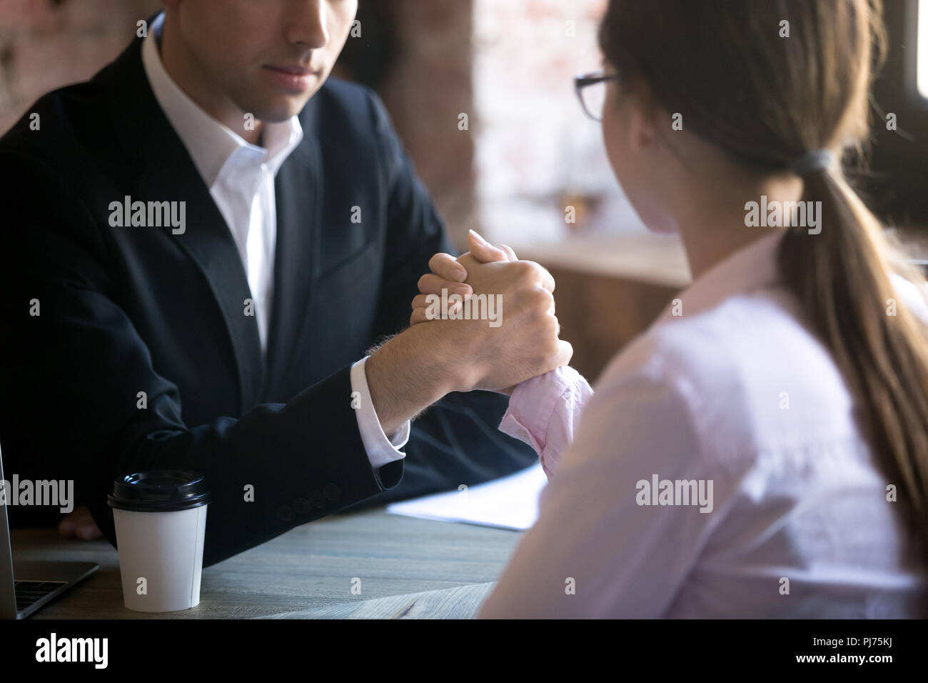 Ernster Mann und Frau armwrestling am Arbeitsplatz Stockfoto