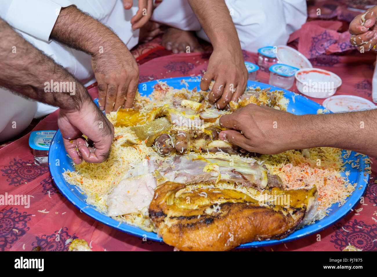 Abu Dhabi, VAE - 26. Juli 2018: die Hände einer Gruppe von arabischen Männer erreichen für traditionelle Mahlzeit von Lamm und Reis beim Essen mit den Händen Stockfoto