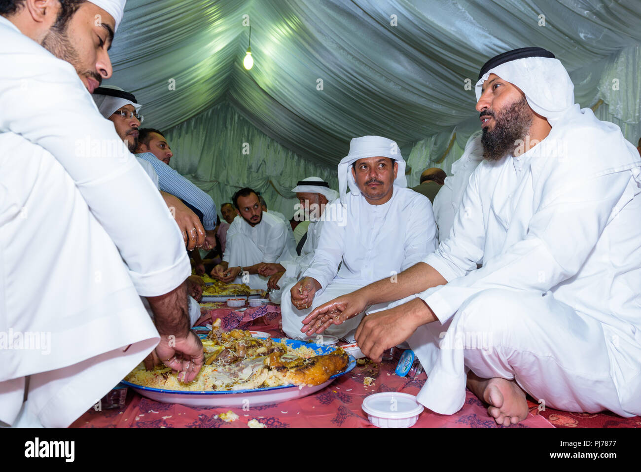 Abu Dhabi, VAE - 26. Juli 2018: Eine Gruppe von arabischen Männer in eine traditionelle Mahlzeit von Lamm und Reis beim Essen mit den Händen Stockfoto