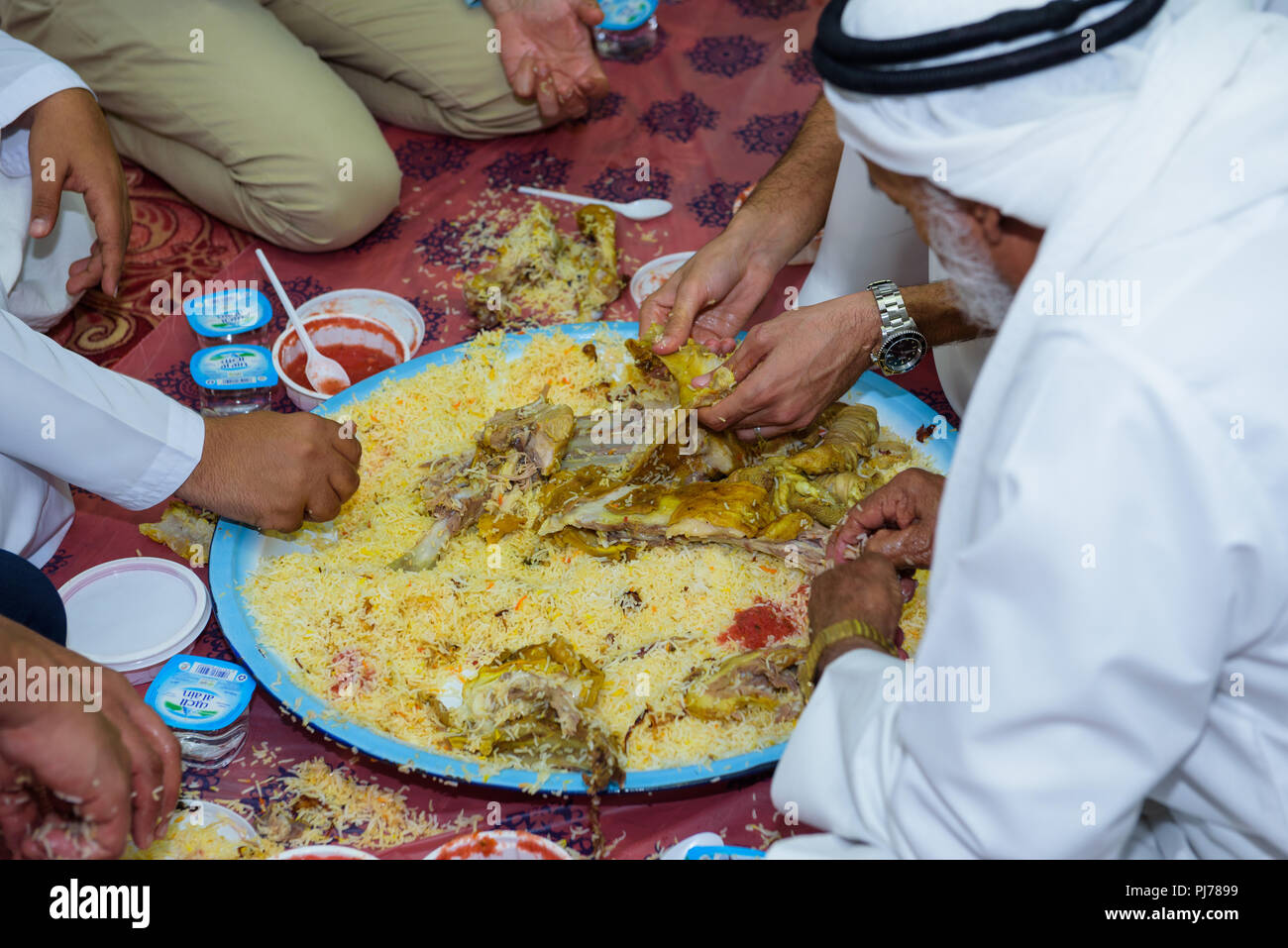 Abu Dhabi, VAE - 26. Juli 2018: Eine Gruppe von arabischen Männer in eine traditionelle Mahlzeit von Lamm und Reis beim Essen mit den Händen Stockfoto