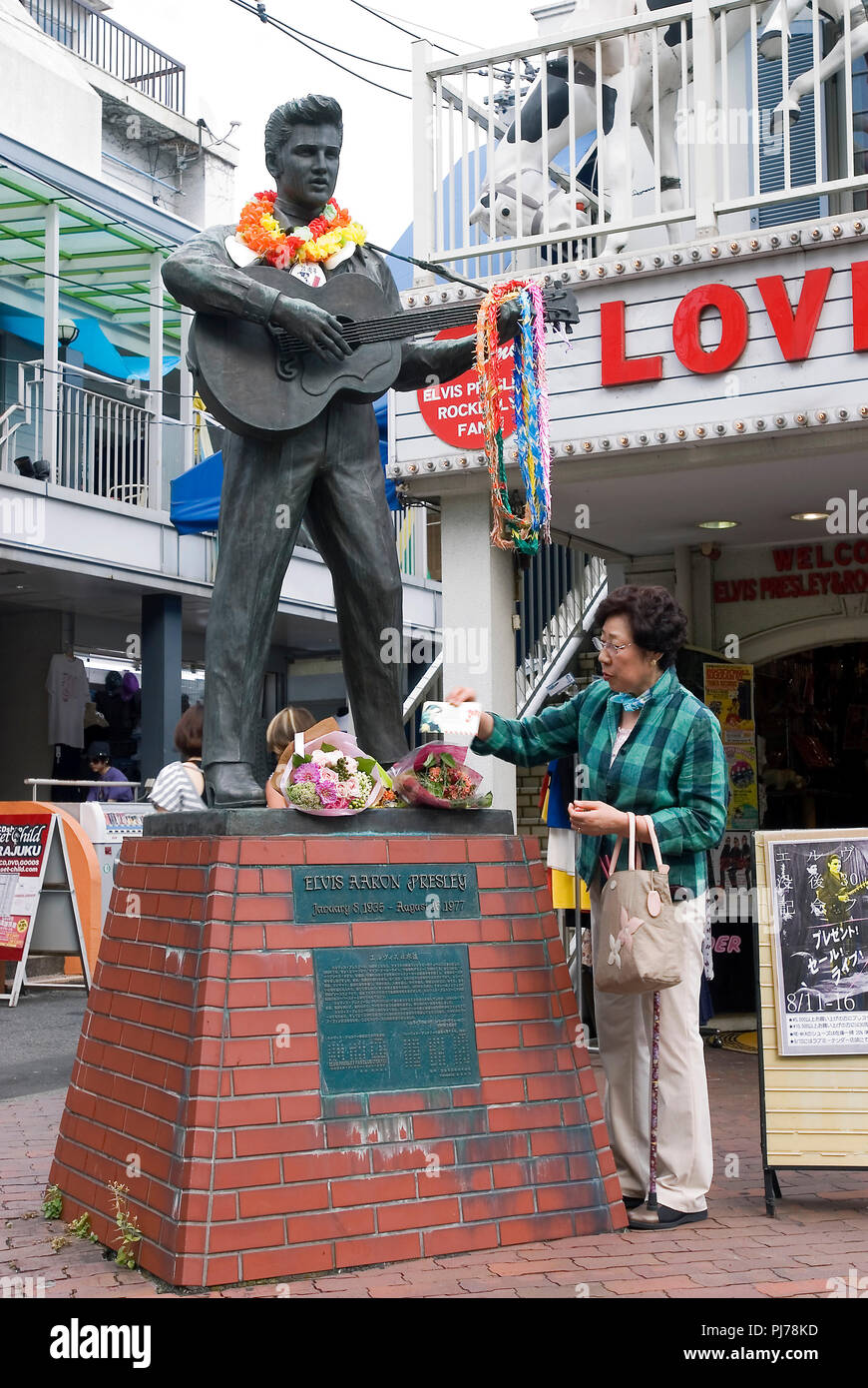 Eine Frau legt eine Karte neben Blumen, zu Füßen der Statue von Elvis Presley in Tokio am Donnerstag, 16. August 2007 zu c festgelegt worden sind Stockfoto