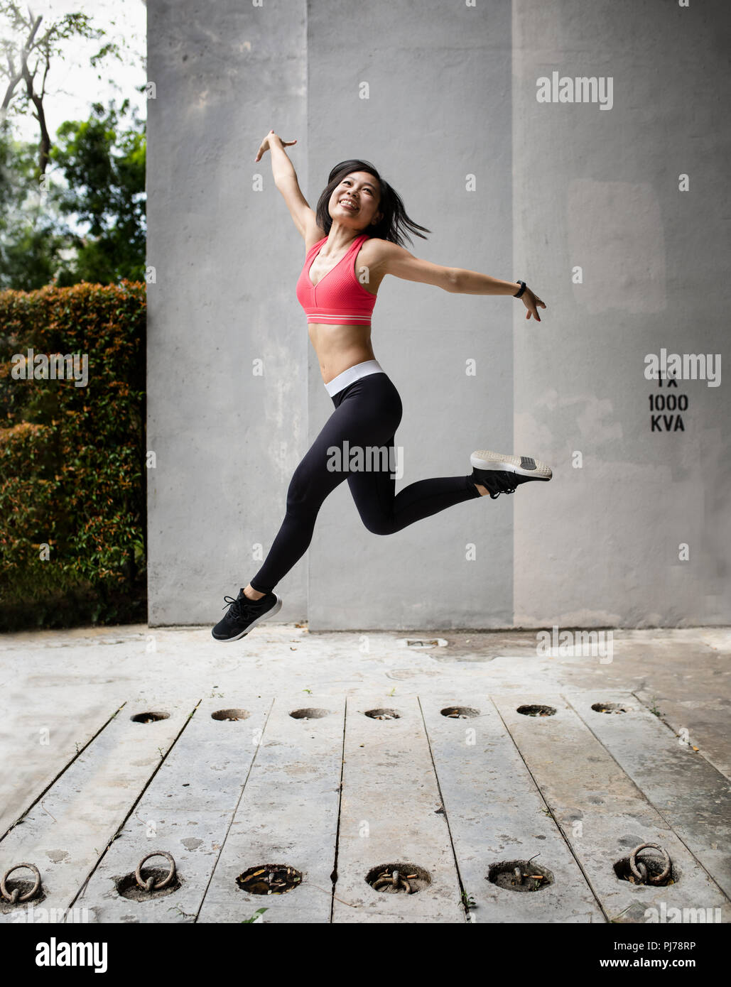 Junge Frau vor Freude hüpfend in städtischen Umgebung Stockfoto