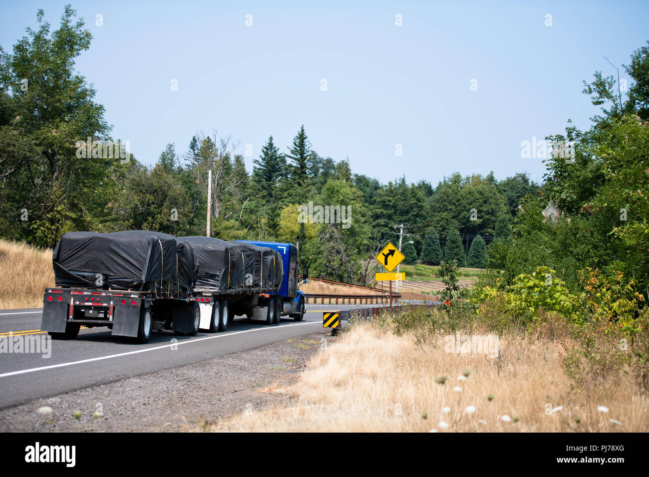 Transport von Holz in Form von Platten, squared Trägern und anderen Arten von verarbeitetem Holz ist auf flachen Bett Big Rig Semi Truck tr durchgeführt Stockfoto