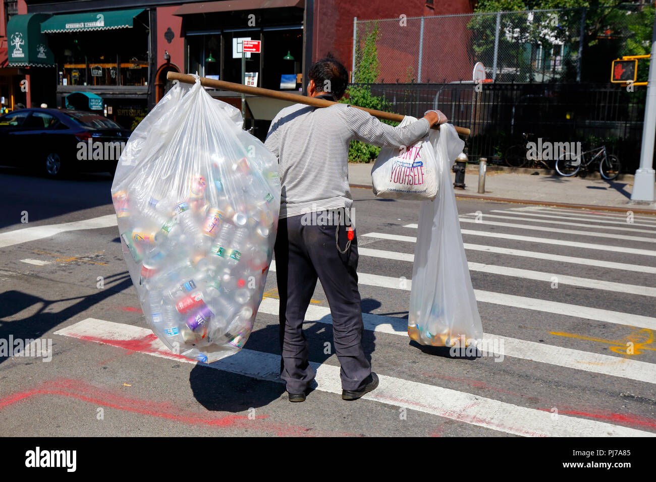 Eine asiatische Person, die Taschen mit recycelbaren Flaschen und Dosen auf einem Schultermast trägt. Viele Menschen, vor allem ältere Chinesen, sind von den ... abhängig Stockfoto