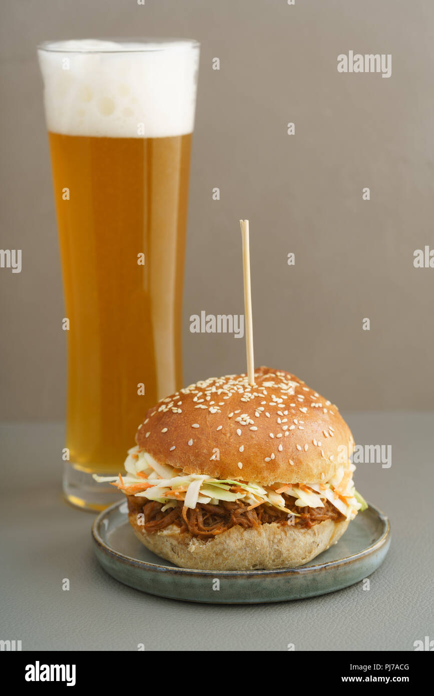 Zog Schweinefleisch Burger mit hausgemachten Burger Brötchen, zog Schweinefleisch und Krautsalat mit einem Glas Bier Stockfoto