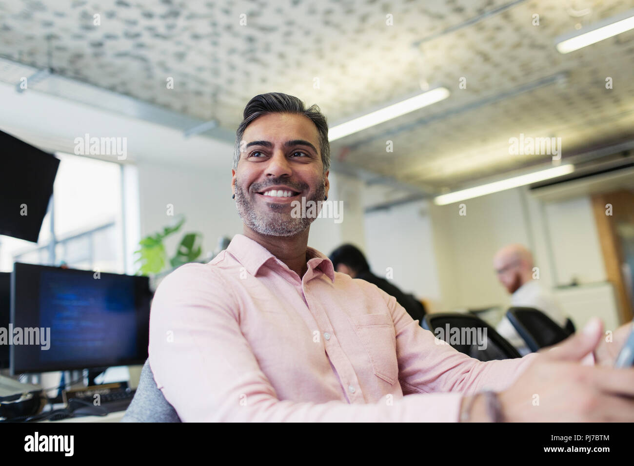 Lächelnd, zuversichtlich Geschäftsmanns, der im Büro Stockfoto