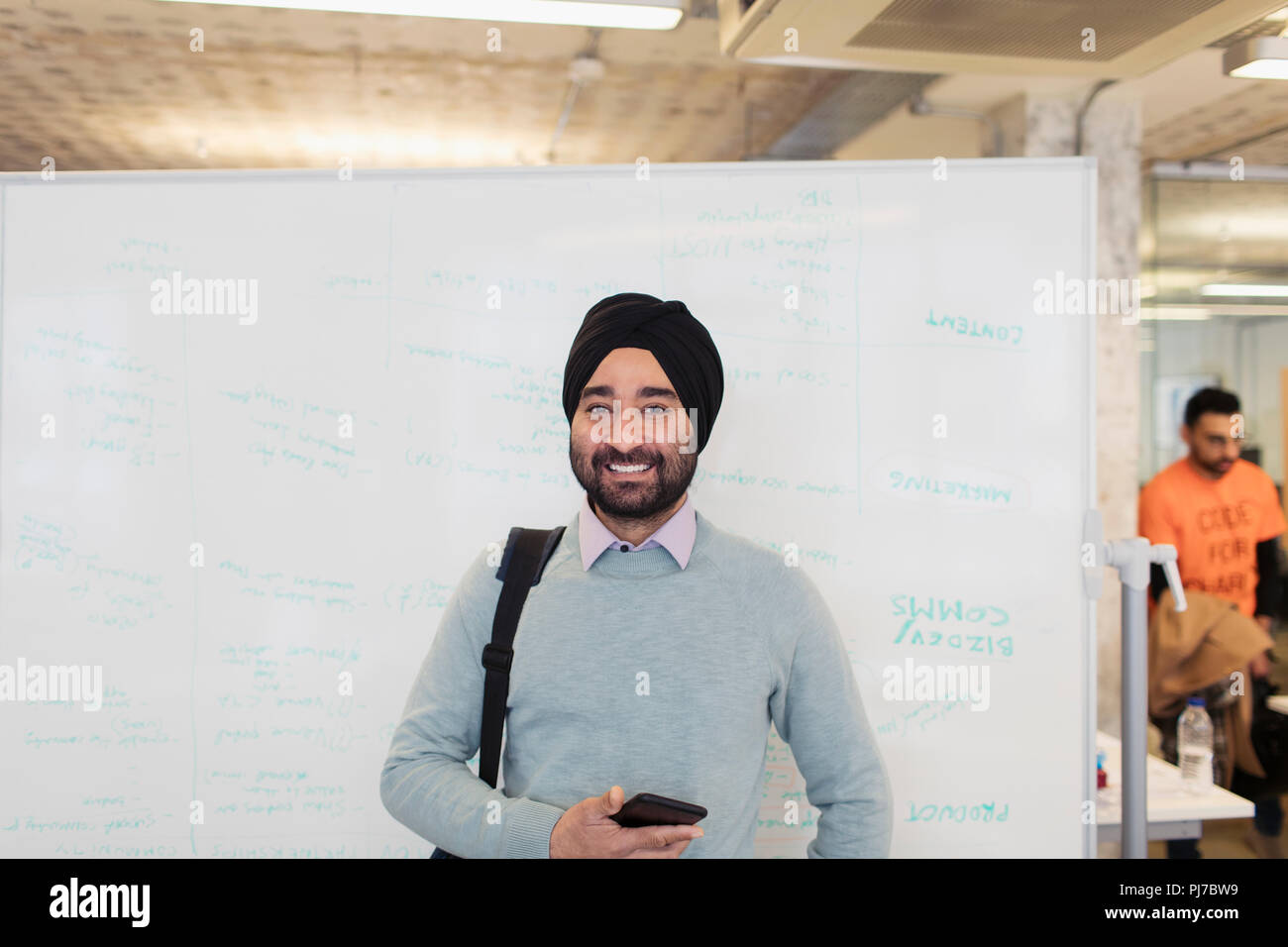 Porträt Lächeln, selbstbewussten indischen Geschäftsmann in Turban am Whiteboard im Büro Stockfoto