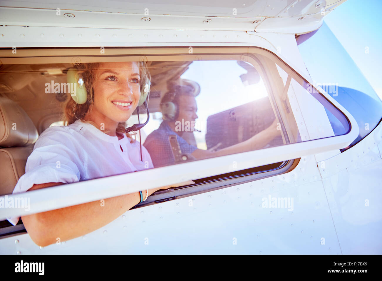 Lächelnde Frau reiten in kleinen Flugzeug Stockfoto