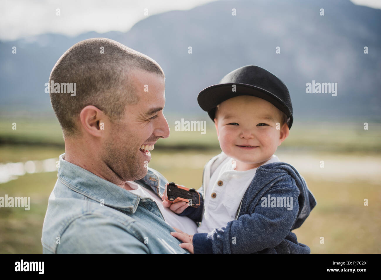 Vater Holding niedlich, Happy Baby Sohn gesucht an Kamera Stockfoto