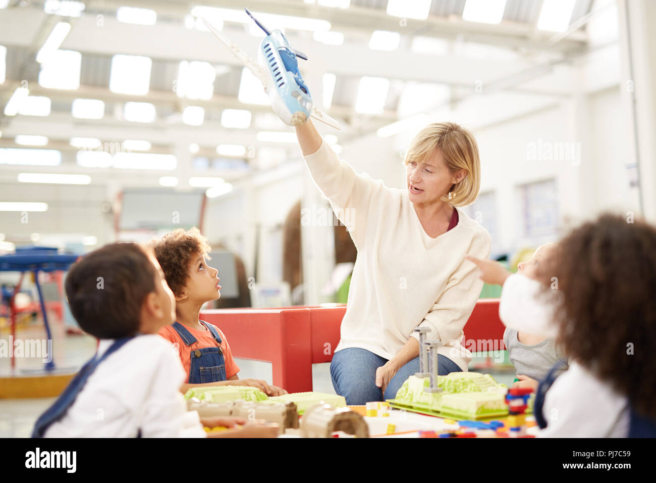 Neugierige Kinder beobachten Lehrer mit Spielzeug Flugzeug in Science Center Stockfoto
