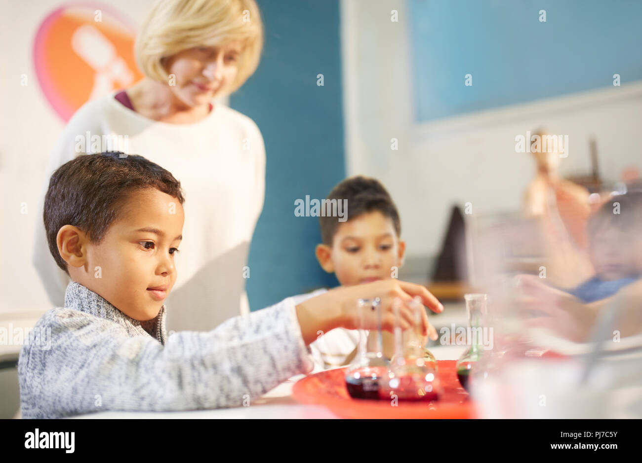 Lehrer beobachten neugierige Schüler spielen mit Becher auf der interaktiven Ausstellung in Science Center Stockfoto