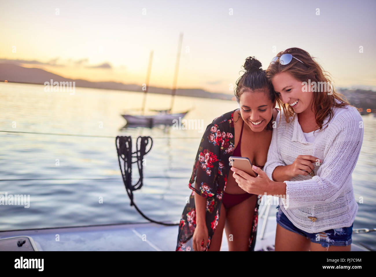 Junge Frauen Freunde mittels Smart Phone auf dem Boot Stockfoto