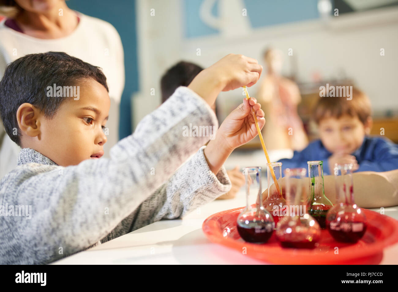 Neugierige Junge mit Pipette in Becher auf der interaktiven Ausstellung in Science Center Stockfoto