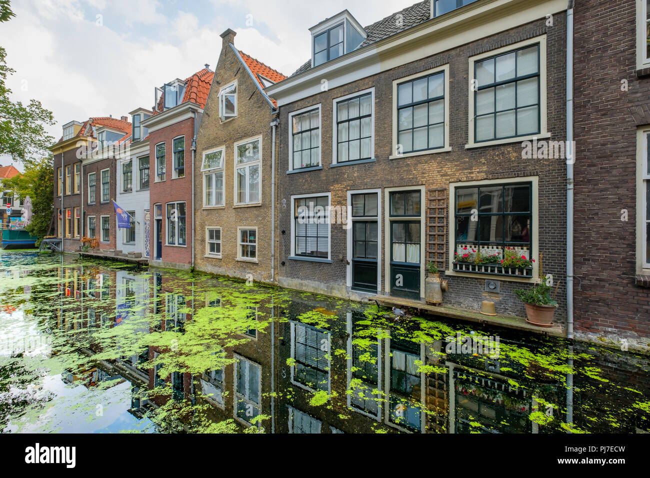 Alte Grachtenhäuser mit schönen Reflexionen im Wasser im Zentrum von Delft, Niederlande. Stockfoto