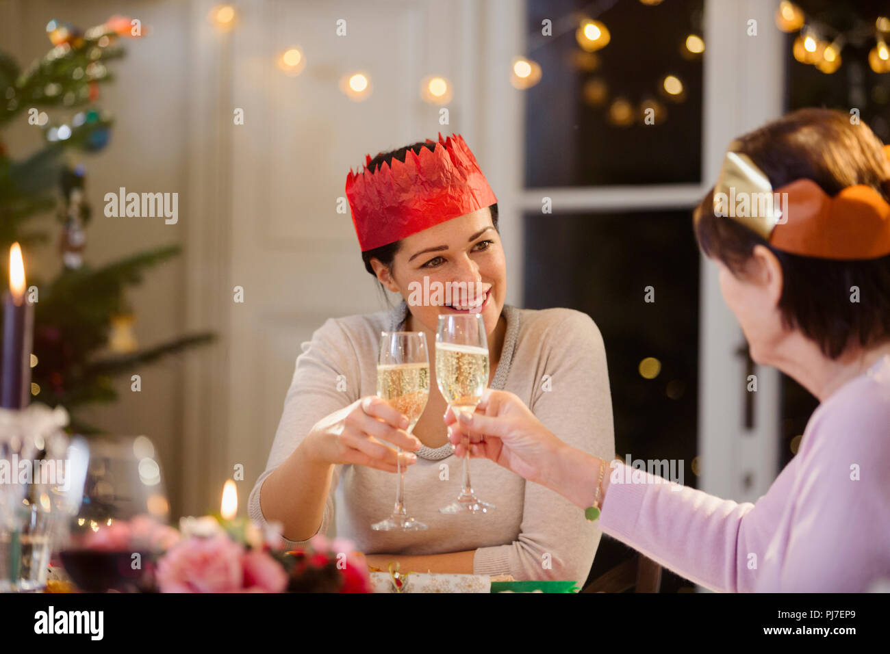 Tochter und Mutter in Papier Kronen toasten Champagner Gläser an Weihnachten Tisch Stockfoto
