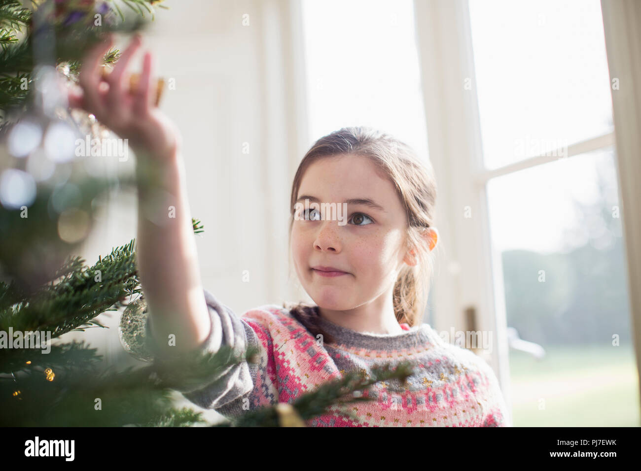 Neugierige Mädchen berühren Ornament am Weihnachtsbaum Stockfoto
