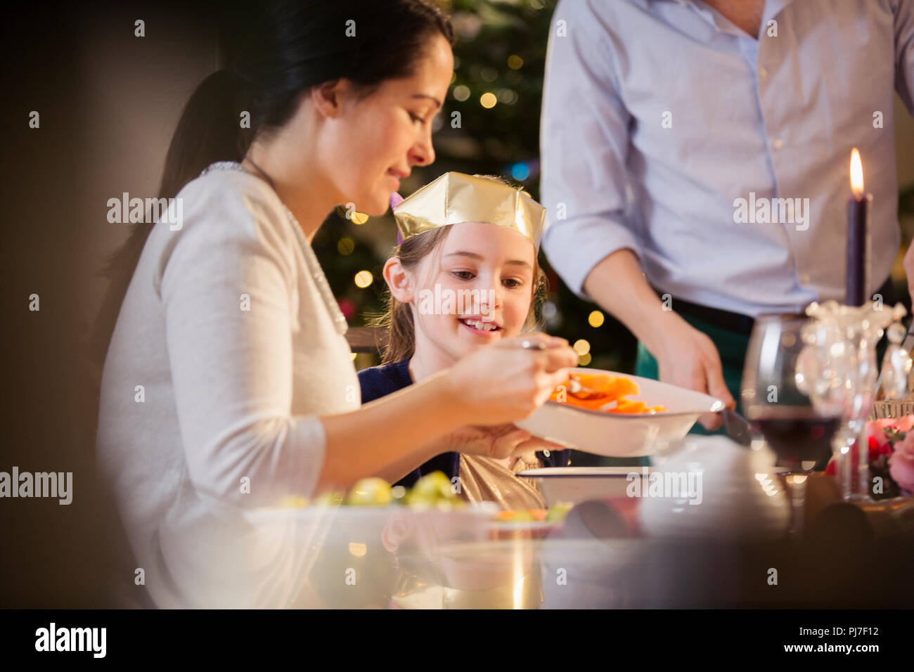 Mutter mit Karotten zu Tochter in Papier Krone an Weihnachten Abendessen Stockfoto