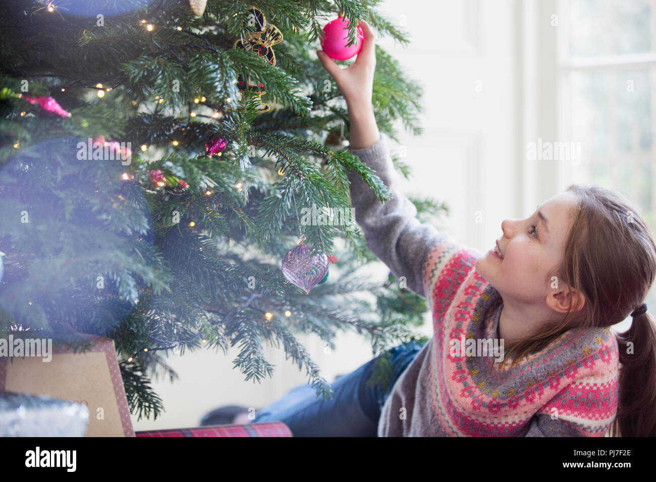 Neugierige Mädchen berühren Ornament am Weihnachtsbaum Stockfoto