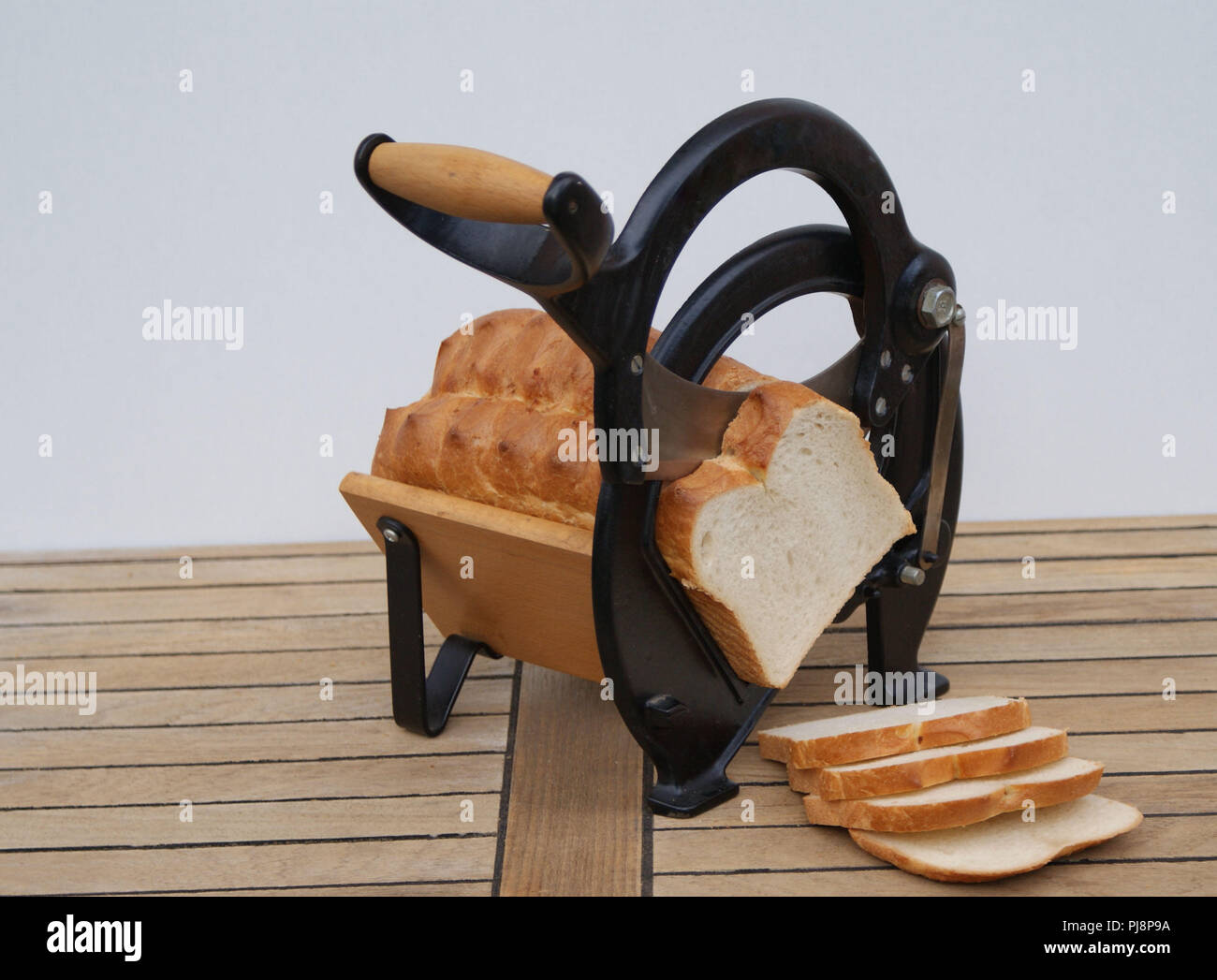 Alte Dänische Brotschneidemaschine auf hölzernen Hintergrund mit weißen Scheiben Brot Stockfoto