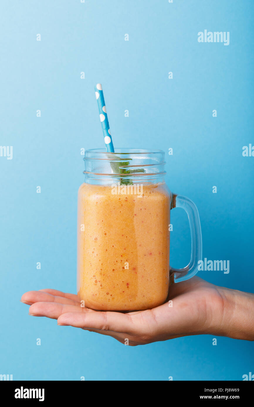 Frisch Smoothies aus reifen Melone in der Hand vorbereitet auf blauem Hintergrund, Nahaufnahme Stockfoto