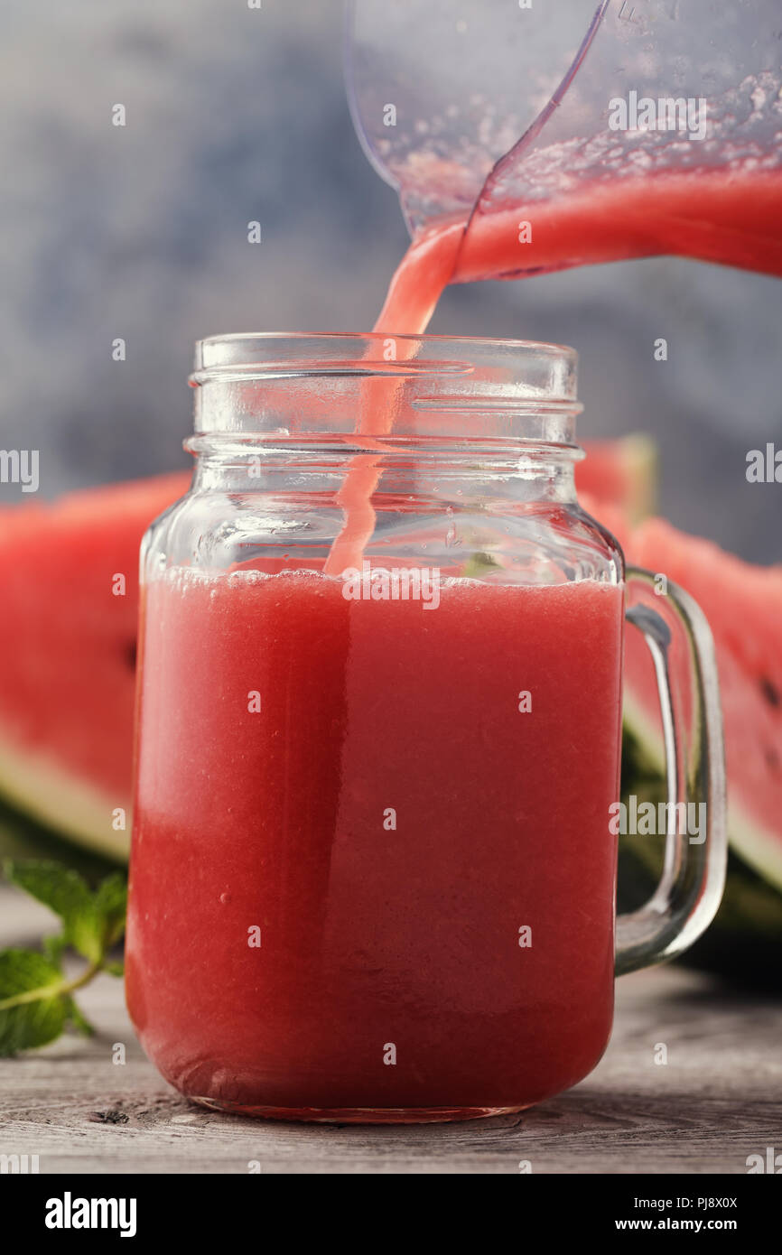Prozess der gießen Smoothies in einen Glasbehälter. Getränk aus Schichten der Wassermelone, close-up Stockfoto