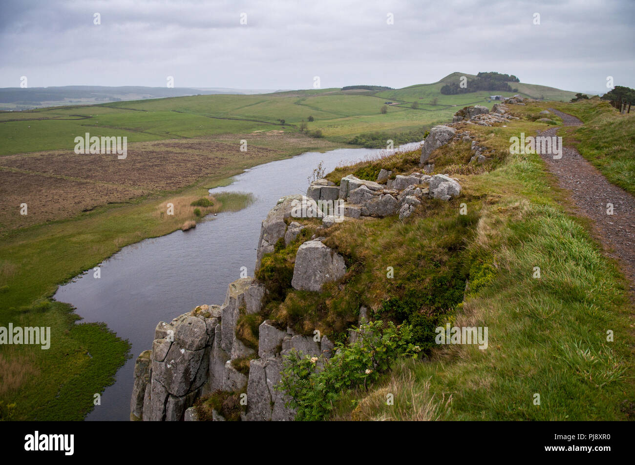 Ein kleiner See, Crag Lough, sitzt unter Felsen unterhalb der Route der Hadrian's Wall in Northumberland, England. Stockfoto