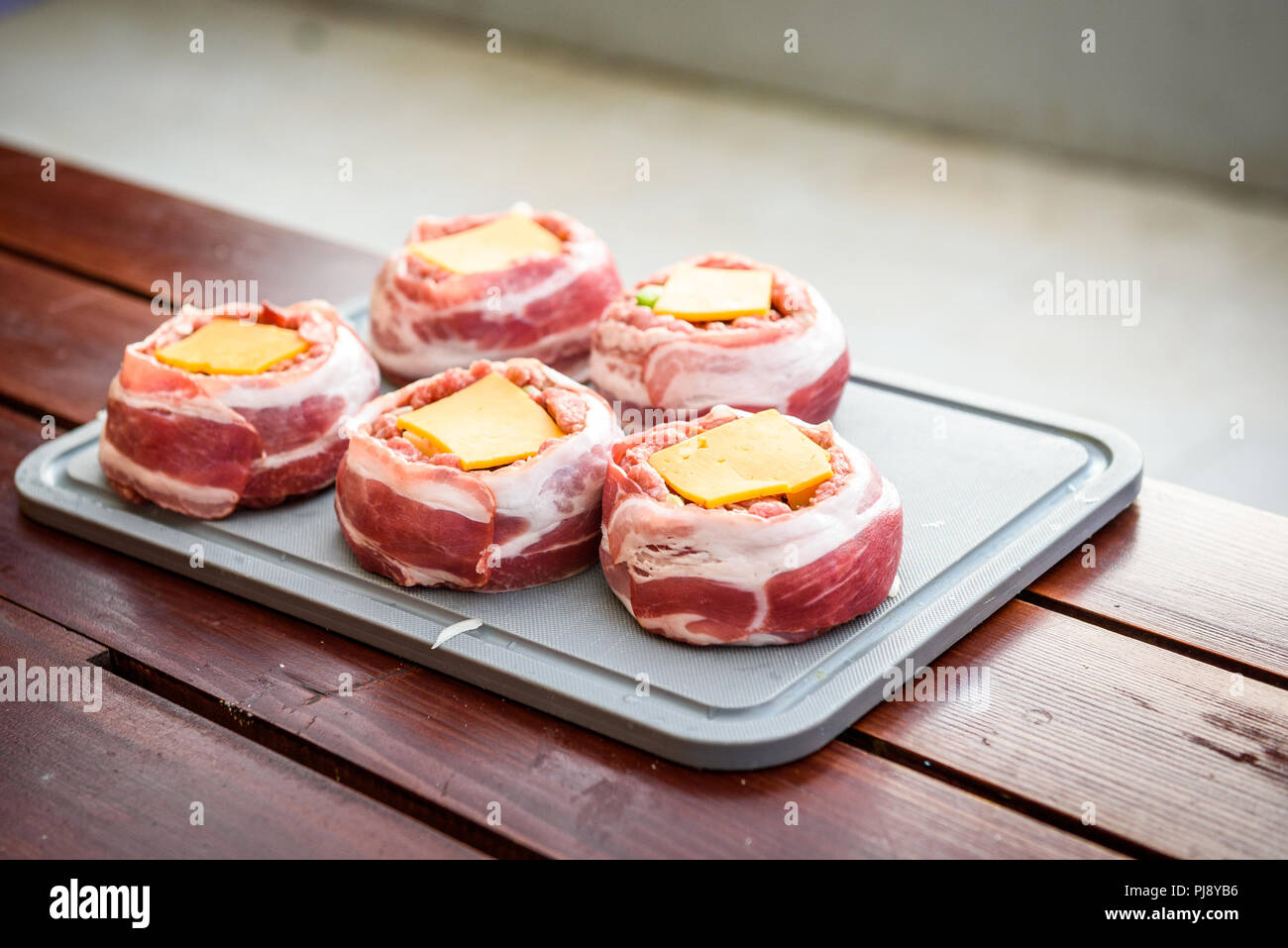 Die hausgemachte Bier kann Bacon Burger am Grill zubereitet. Vorbereitung gefüllte Pastetchen, in Speck umwickelt. Stockfoto