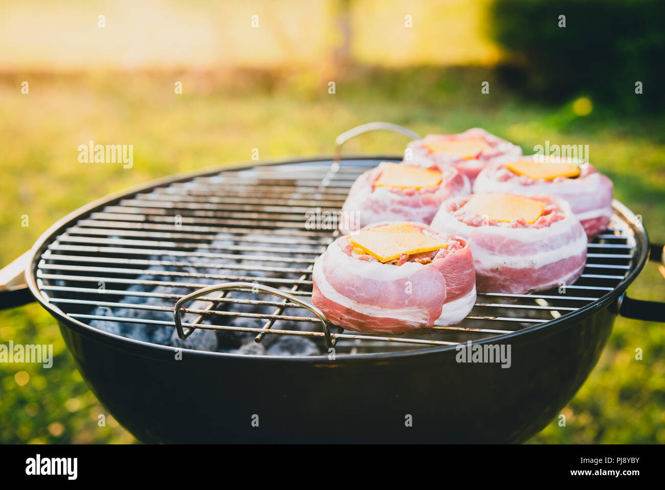 Die hausgemachte Bier kann Bacon Burger am Grill zubereitet. Vorbereitung gefüllte Pastetchen, in Speck umwickelt und Grillen auf indirekte Hitze in der Natur an der Bac Stockfoto