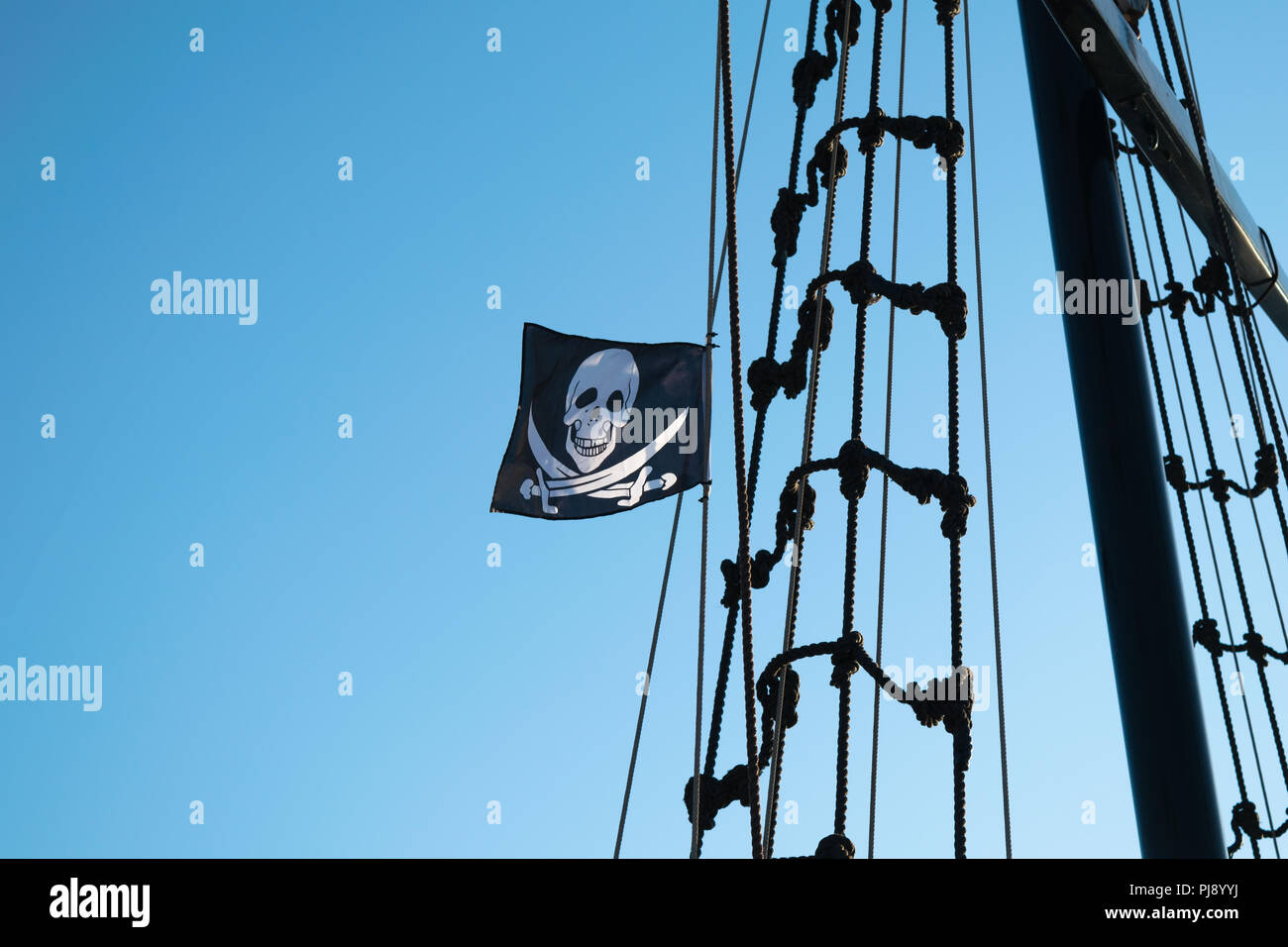 Angehobene Jolly Roger Piratenflagge auf einem Schiff mast. Stockfoto