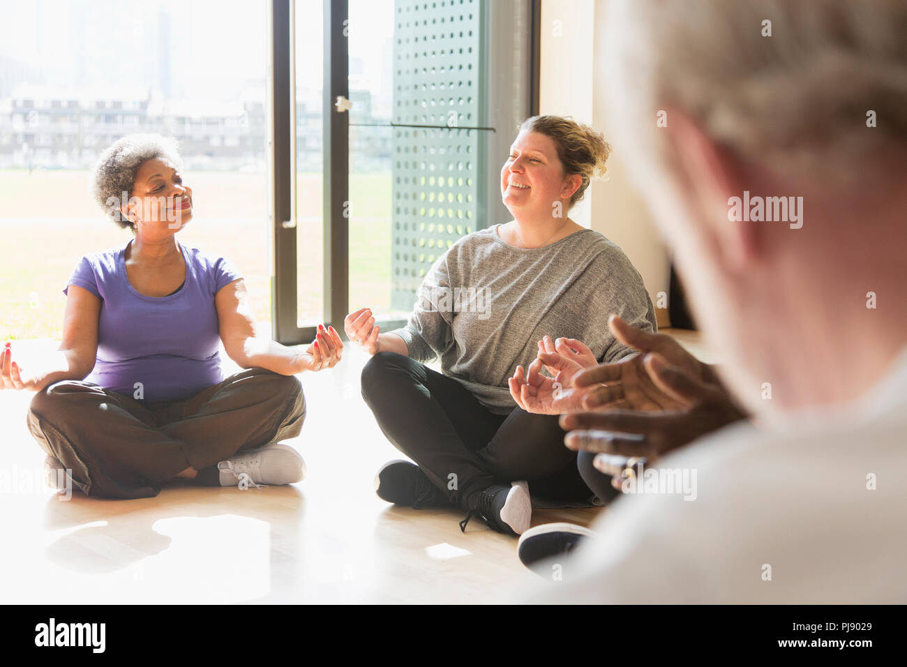 Lächelnd, serene Frauen Meditation in sonnigen Fenster Stockfoto