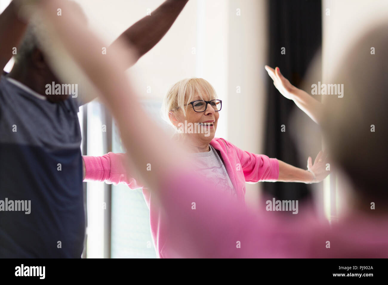 Lächelnd Active Senior Frau stretching Waffen in Ausübung Klasse Stockfoto