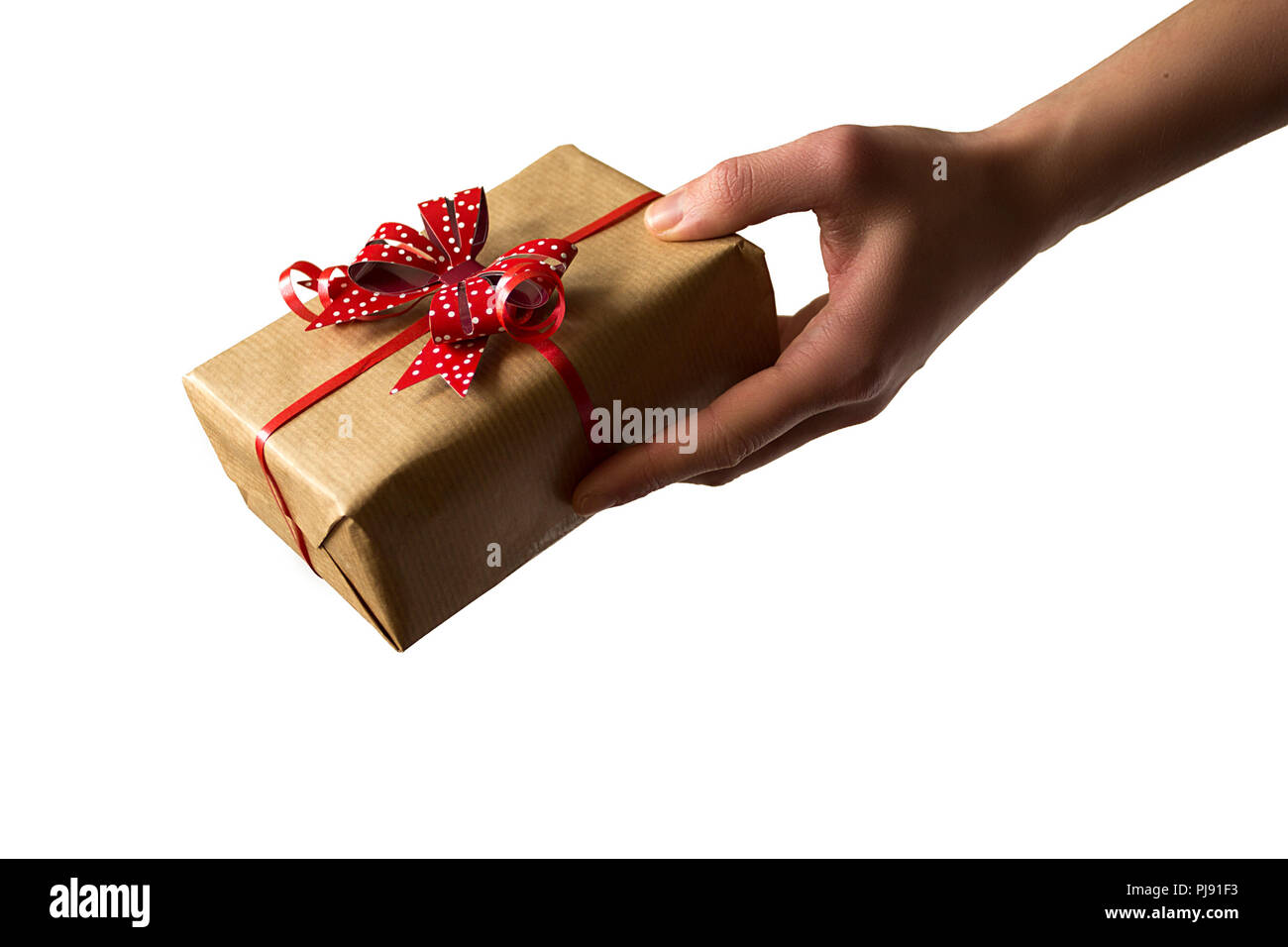 Weibliche Hand, die eine Geschenkverpackung mit roter Schleife. Geschenke geben isoliert auf Weiss. Stockfoto