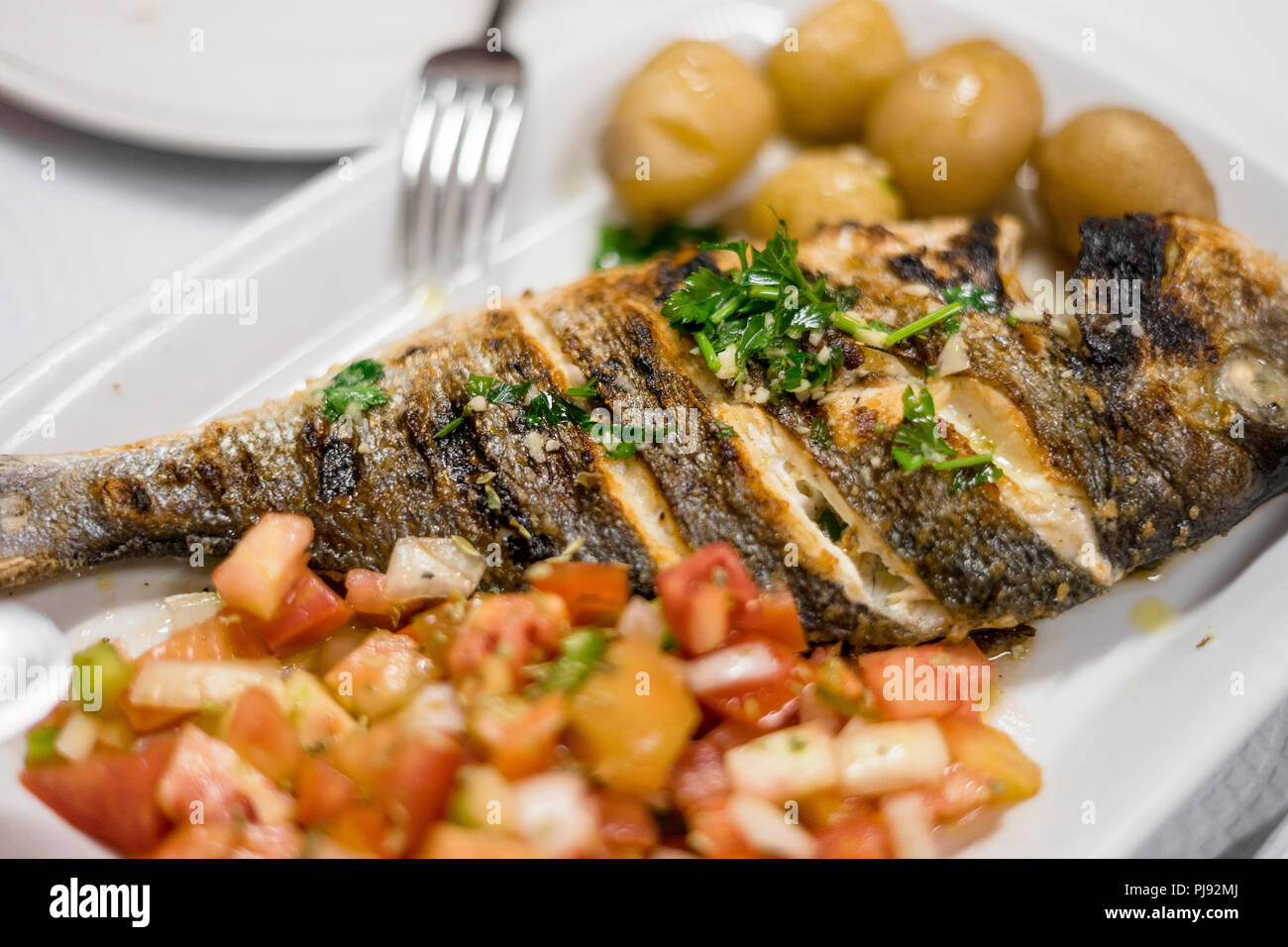 Traditionelle portugiesische Gegrillte goldener Fisch mit Kartoffeln und Salat serviert. Stockfoto