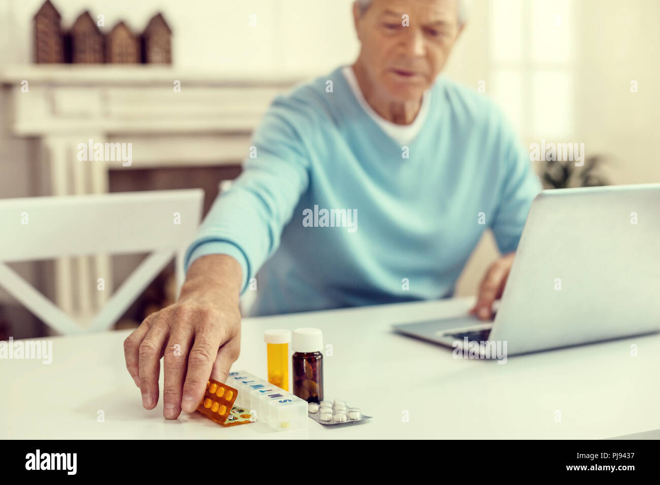Senior gentleman seine Pillen nehmen am Tisch Stockfoto