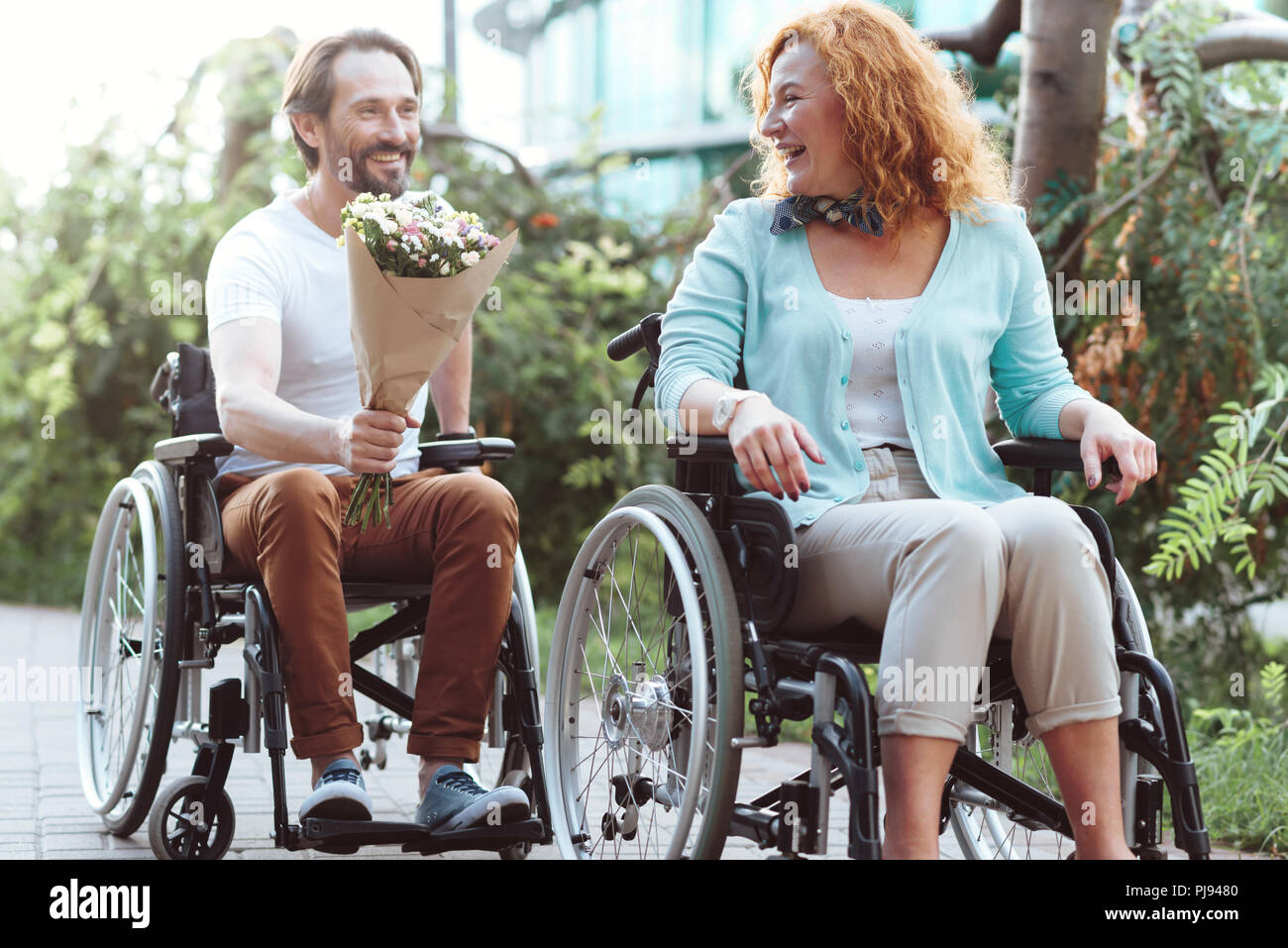 Aufgeregt Frau empfangen Blumenstrauß während der Fahrt ihren Rollstuhl Stockfoto