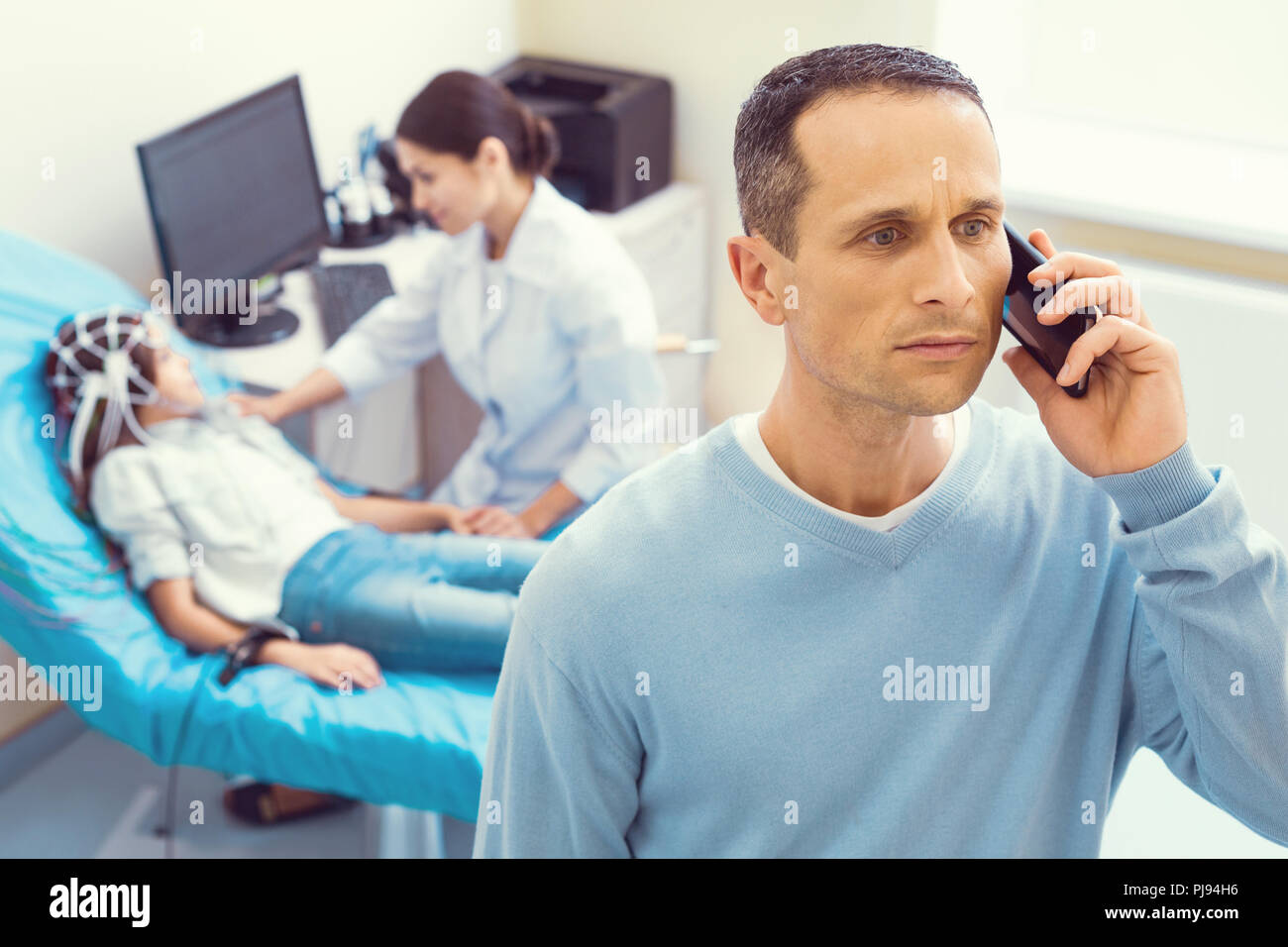 Angst Vater am Telefon sprechen, während die Tochter in der elektroenzephalographie Stockfoto