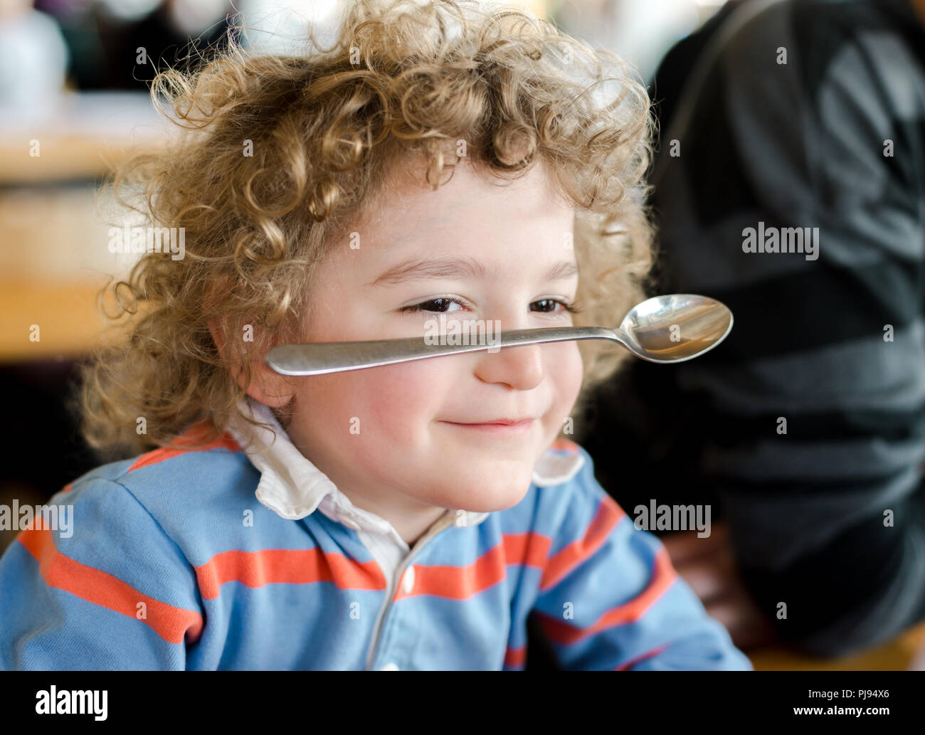 Junge Junge lächelt als er gleicht einem Löffel auf der Nase als Partei trick Stockfoto