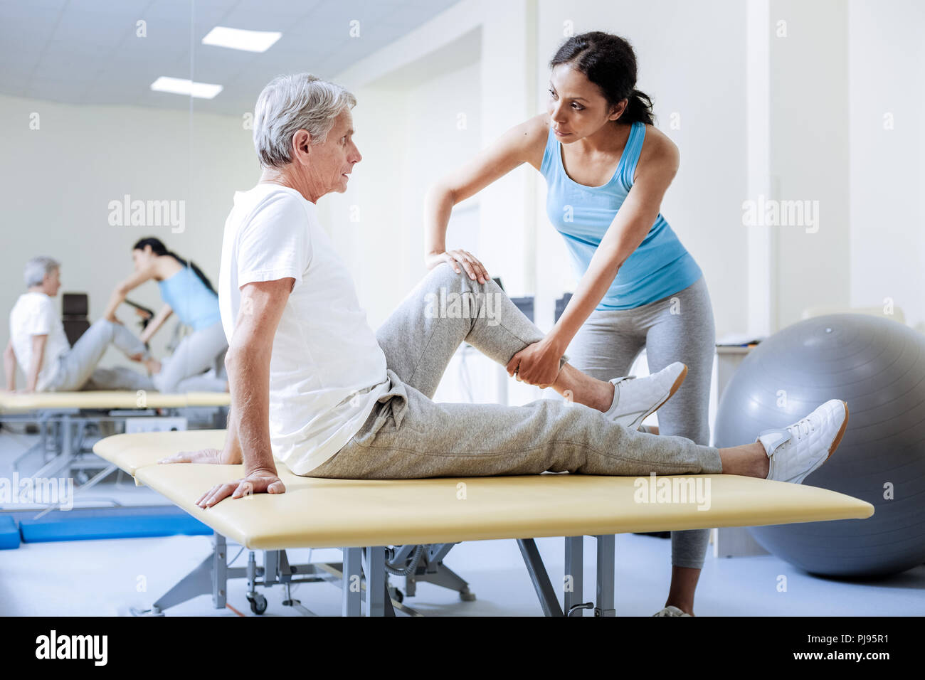 Ruhe aufmerksam medizinischer Arbeiter Erwärmung der verletzte Muskeln ihrer Patienten Stockfoto