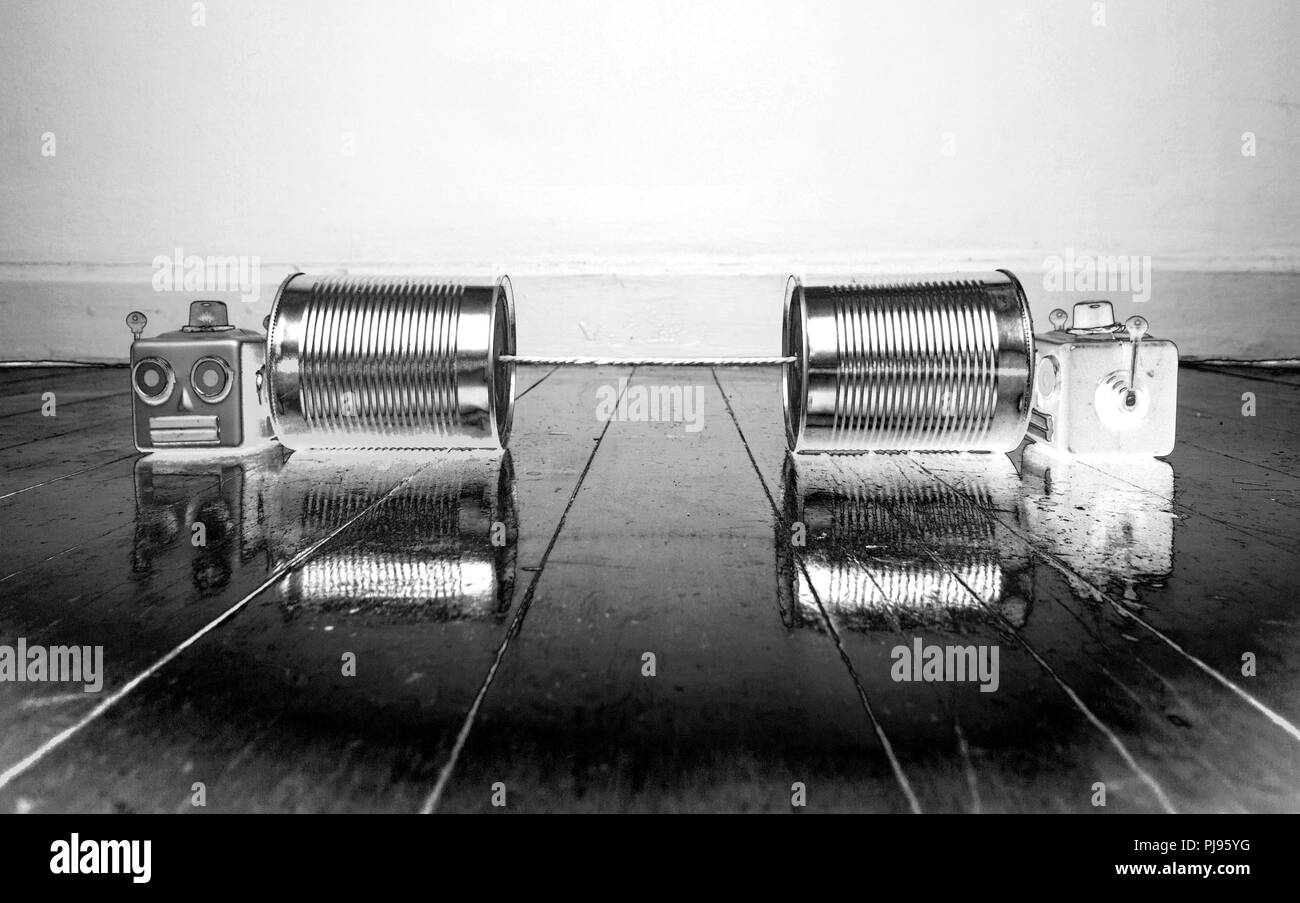 Retro Robotern auf blechdose Telefone auf einem Holzboden mit Reflexion solarisiert Schwarzweiß Stockfoto
