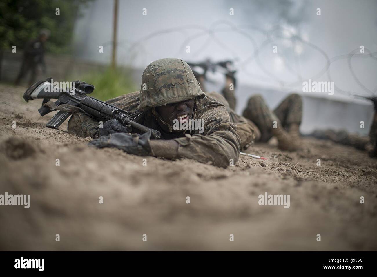 Us Marine Corps Recruit Jovan Jones, mit Platoon 2057, Echo, 2. rekrutieren Ausbildung Bataillon, kriecht auf dem Boden entlang zwischen Hindernisse bei der Warrior Training Juli 6, 2018 auf Parris Island, S.C. Rekruten in Teams von vier über und unter verschiedenen Hindernisse wie Concertina wire, Mauern und kleinen Gräben beim Tragen der Bekämpfung der Ausrüstung während der Krieger Training manövrierte. Echo ist zu graduieren, Nov. 14, 2018 geplant. Stockfoto